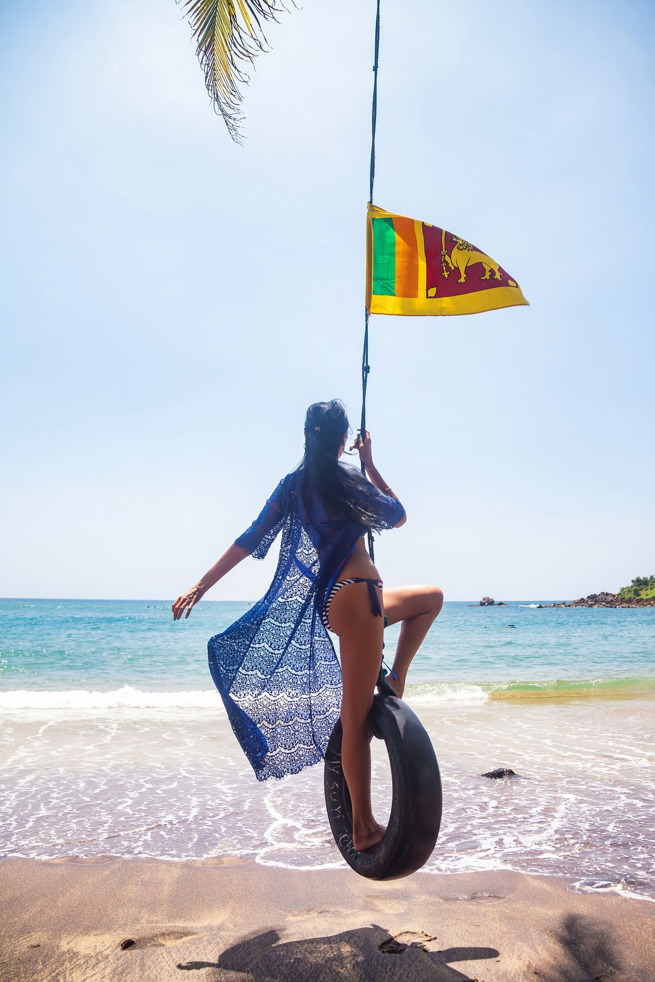 Rear view woman in blue swimwear swing on bungee with Sri Lankan flag
