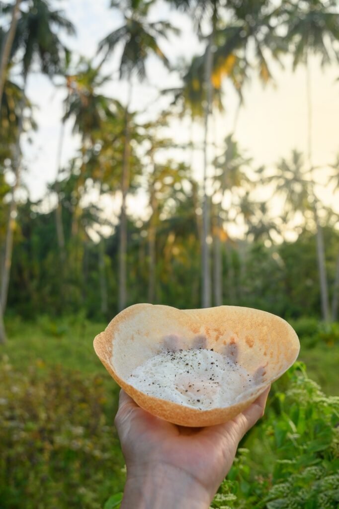 Sri lankan street food egg hopper in woman's hand. Close up. Local food. Outdoors. bittara appa.