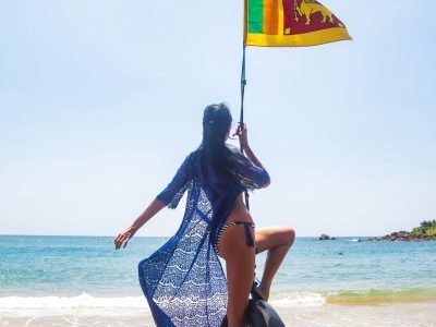 Rear view woman in blue swimwear swing on bungee with Sri Lankan flag